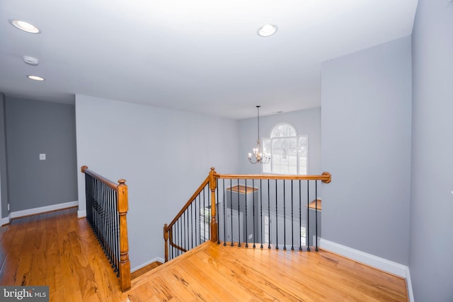 staircase with hardwood / wood-style flooring and an inviting chandelier