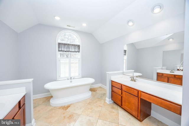 bathroom featuring lofted ceiling, vanity, tile patterned flooring, and a bathing tub