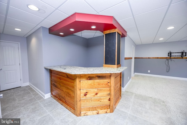 bar with a paneled ceiling and light colored carpet