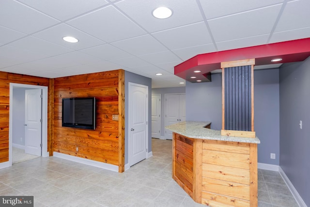 kitchen featuring a drop ceiling, wood walls, and light brown cabinets