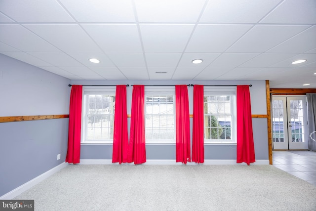 carpeted spare room with a paneled ceiling, french doors, and a healthy amount of sunlight