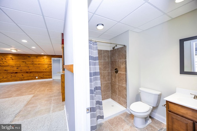 bathroom with a paneled ceiling, wood walls, vanity, toilet, and a shower with shower curtain