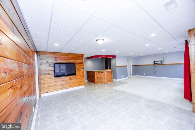 basement with a paneled ceiling and wooden walls