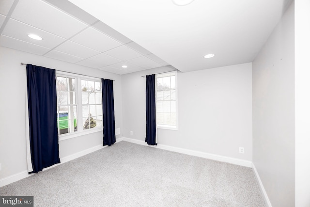 carpeted empty room featuring a paneled ceiling and plenty of natural light