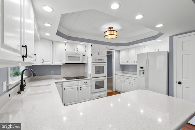 kitchen featuring a tray ceiling, white appliances, and white cabinets