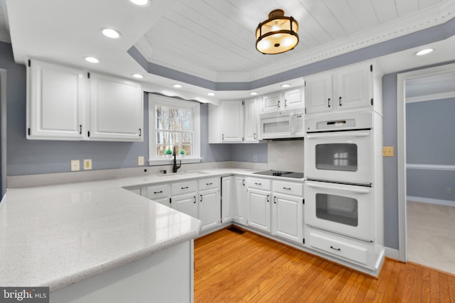 kitchen featuring white appliances, white cabinets, a sink, and light countertops