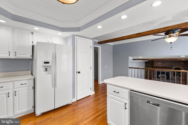 kitchen featuring white refrigerator with ice dispenser, white cabinetry, light countertops, and stainless steel dishwasher