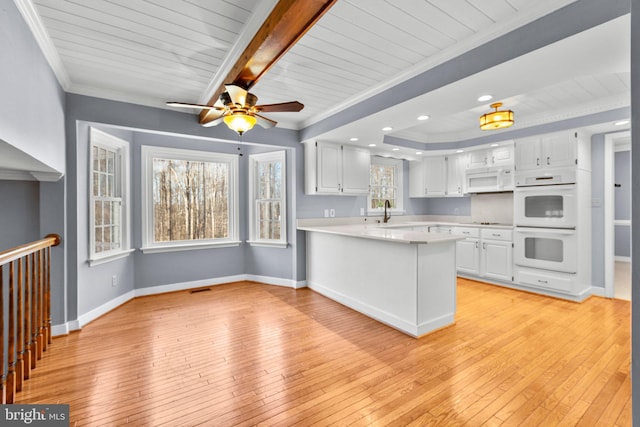 kitchen with light countertops, white appliances, a peninsula, and white cabinets