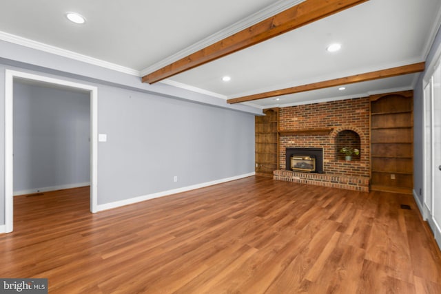 unfurnished living room featuring ornamental molding, beamed ceiling, built in shelves, and baseboards