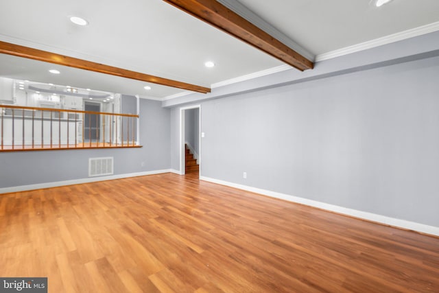 unfurnished living room featuring light wood finished floors, baseboards, visible vents, and beam ceiling