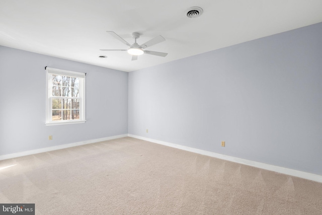 empty room featuring ceiling fan, carpet floors, visible vents, and baseboards