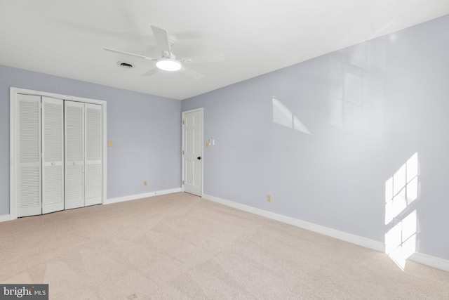 unfurnished bedroom with a closet, light colored carpet, visible vents, a ceiling fan, and baseboards