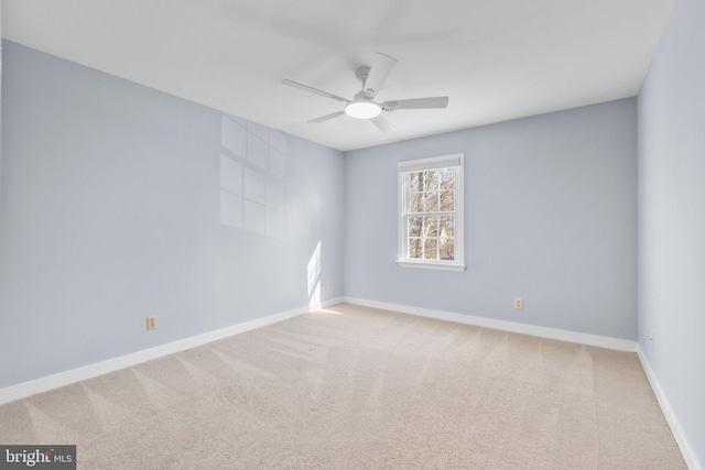 spare room with ceiling fan, baseboards, and light colored carpet