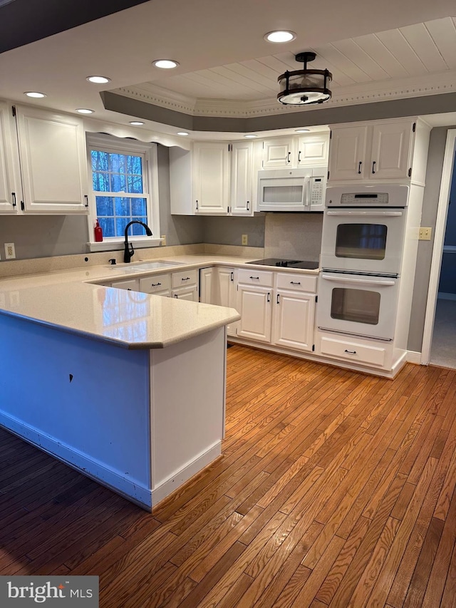 kitchen with white cabinetry, white appliances, and light hardwood / wood-style flooring