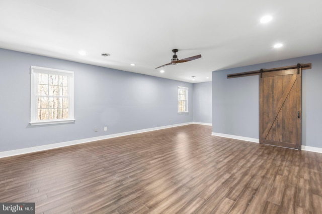 unfurnished living room with a barn door, baseboards, dark wood finished floors, a ceiling fan, and recessed lighting