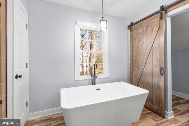 bathroom featuring a healthy amount of sunlight, a freestanding tub, a sink, and wood finished floors