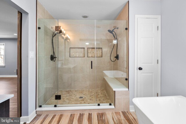 bathroom with wood finished floors, baseboards, a freestanding bath, a closet, and a shower stall