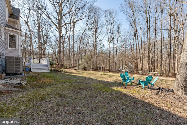 view of yard featuring fence, a wooden deck, and central air condition unit