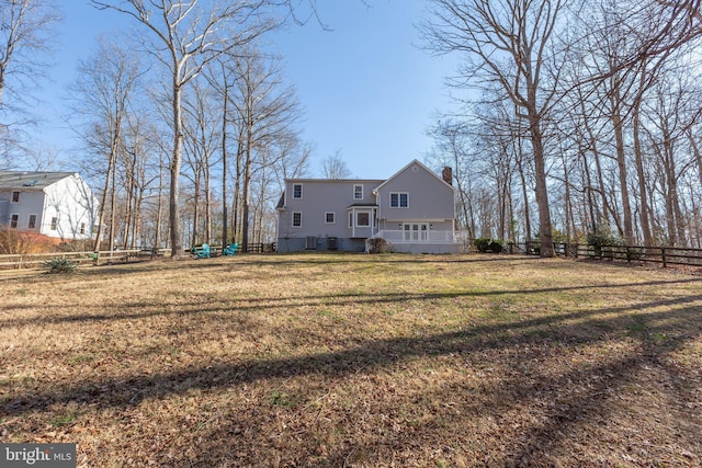 rear view of house featuring a yard, a chimney, and fence