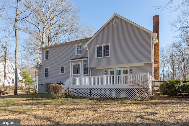 back of house with a chimney, a deck, and a yard