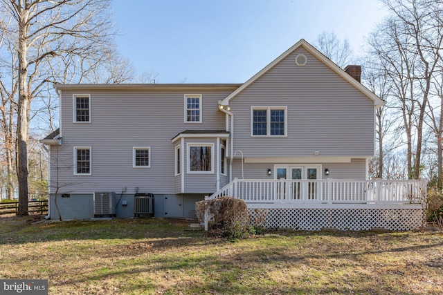 back of house featuring a lawn, a chimney, a wooden deck, and central air condition unit