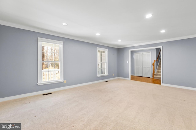 unfurnished room with ornamental molding, stairway, visible vents, and baseboards