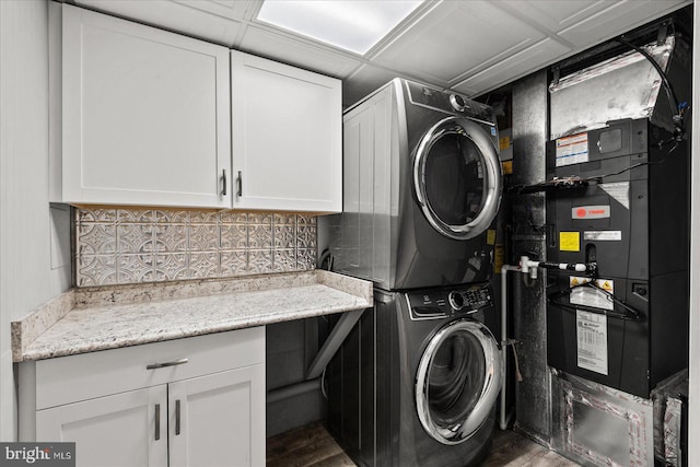 washroom featuring hardwood / wood-style flooring, cabinets, and stacked washer / drying machine