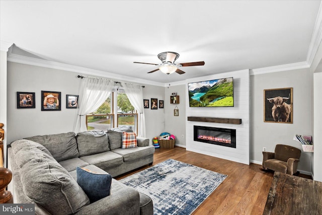 living room with hardwood / wood-style floors, a fireplace, ornamental molding, and ceiling fan