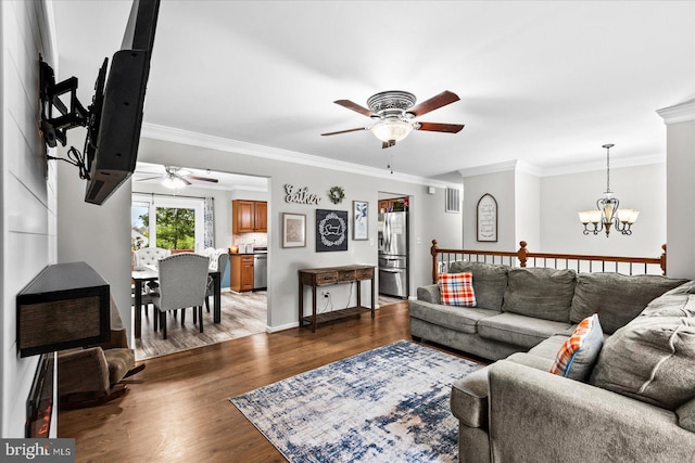 living room featuring ceiling fan with notable chandelier, wood-type flooring, and ornamental molding