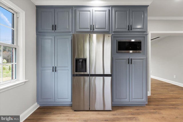 kitchen with ornamental molding, stainless steel fridge, gray cabinets, and light hardwood / wood-style flooring