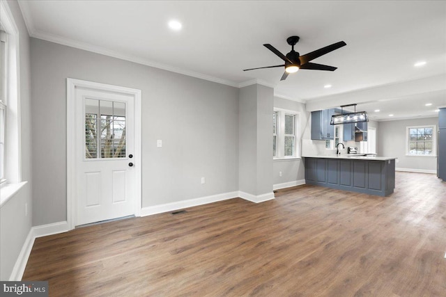 unfurnished living room with wood-type flooring, ornamental molding, and ceiling fan