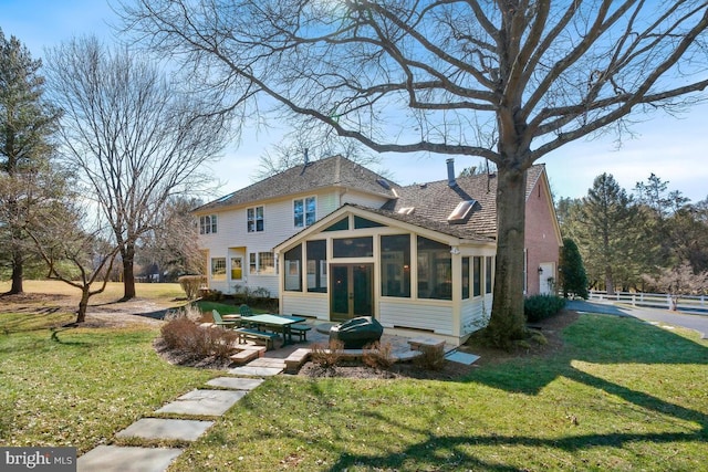 rear view of house with a lawn, a patio, and a sunroom