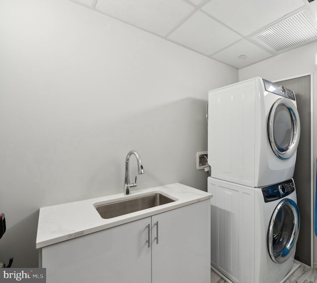 washroom with cabinets, stacked washer / drying machine, and sink