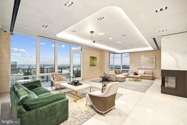 living room with a fireplace, floor to ceiling windows, and a raised ceiling