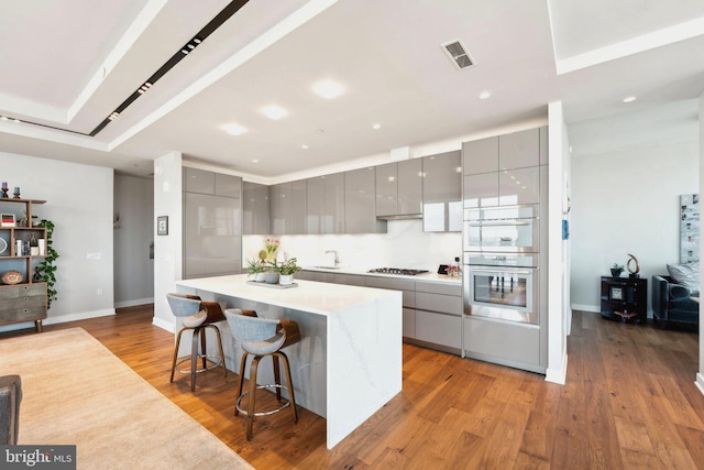 kitchen with stainless steel appliances, gray cabinets, a kitchen breakfast bar, and a kitchen island