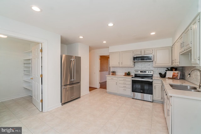 kitchen with light tile patterned flooring, appliances with stainless steel finishes, sink, and backsplash