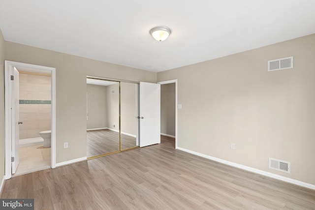 unfurnished bedroom with connected bathroom, a closet, and light wood-type flooring