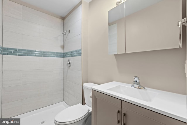 bathroom with vanity, toilet, and a tile shower