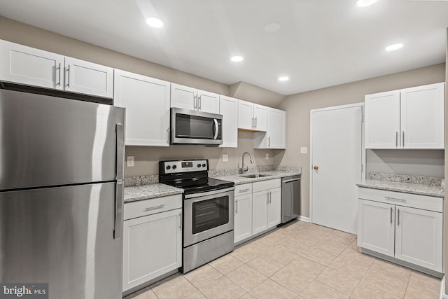 kitchen with sink, white cabinetry, light stone counters, light tile patterned floors, and stainless steel appliances