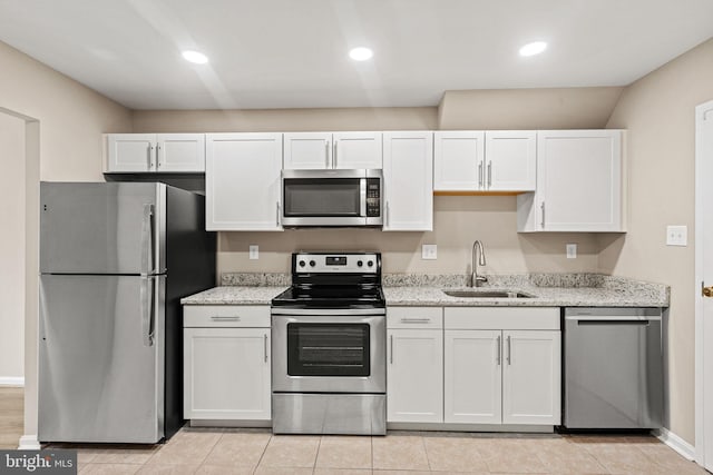 kitchen with appliances with stainless steel finishes, light stone countertops, sink, and white cabinets