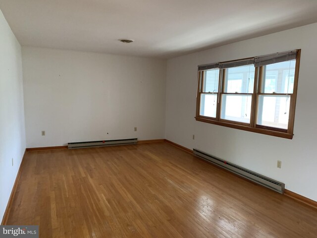 spare room featuring a baseboard radiator and light hardwood / wood-style floors