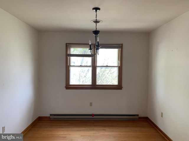 empty room featuring baseboard heating and light hardwood / wood-style floors