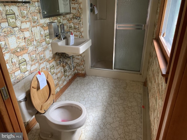 bathroom with toilet, sink, and a shower with door