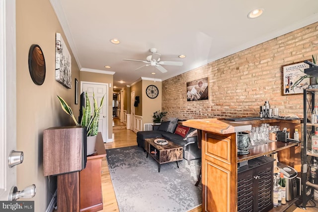 interior space featuring crown molding, brick wall, ceiling fan, and light hardwood / wood-style floors