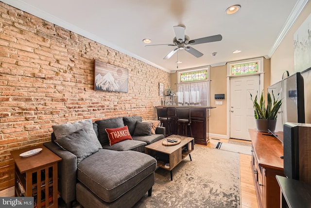 living room featuring crown molding, ceiling fan, brick wall, and light hardwood / wood-style floors