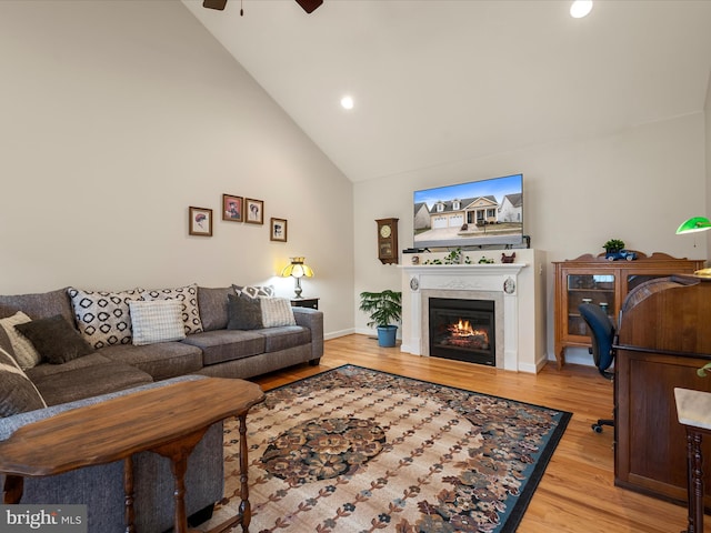 living room with high vaulted ceiling, ceiling fan, and light wood-type flooring