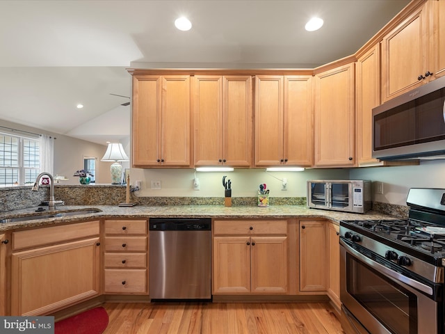 kitchen featuring light stone counters, sink, light hardwood / wood-style flooring, and appliances with stainless steel finishes