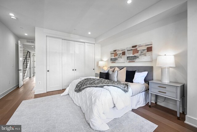 bedroom with dark hardwood / wood-style floors and a closet