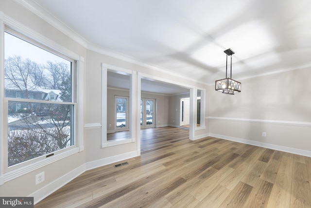 unfurnished dining area featuring hardwood / wood-style floors, ornamental molding, and a chandelier