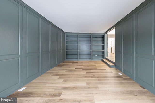 walk in closet with light hardwood / wood-style flooring